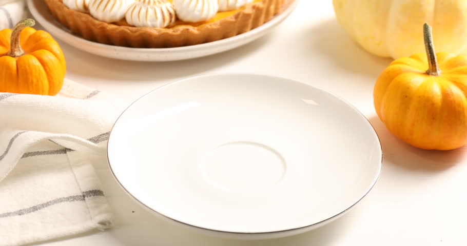 Putting piece of delicious pumpkin pie with meringue onto plate at white table, closeup. Pastry for Thanksgiving day or other fall holiday