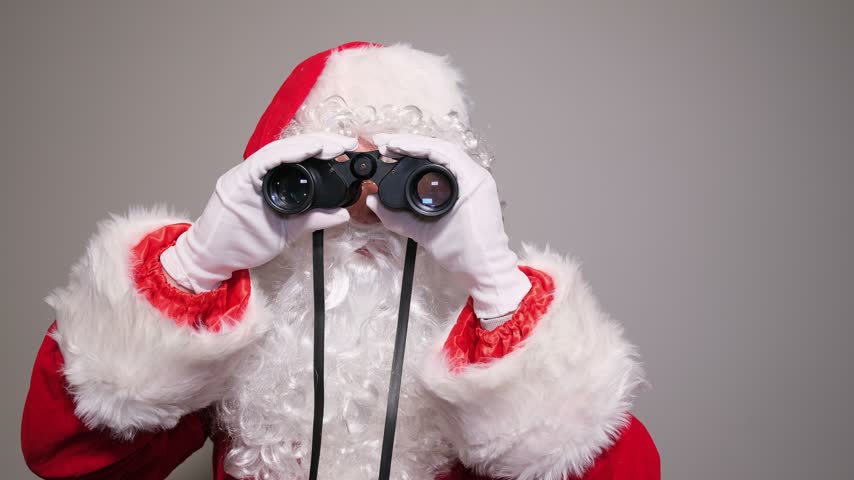 Santa claus looking through binoculars waving hand