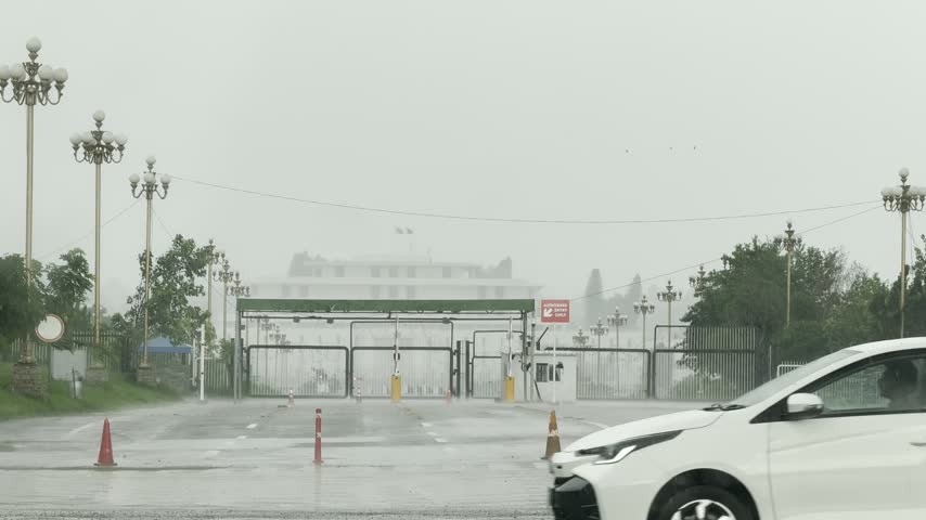Rain falls at the gated National Assembly complex on a wet roadway, Islamabad, Pakistan