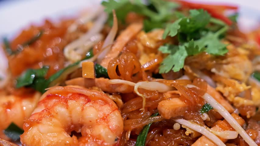 Close-up of freshly cooked Pad Thai with plump shrimp, rice noodles, egg, bean sprouts, and crushed peanuts, presented as a flavorful Thai street food dish.