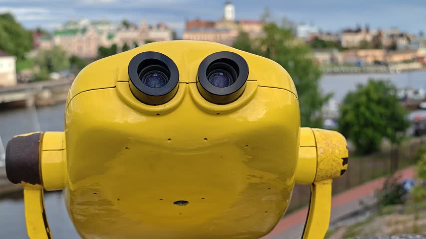 Close-up of a yellow telescope with a city in the background, great for illustrating a scene of urban exploration or astronomy.