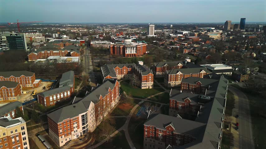Aerial view of University of Kentucky residence halls and academic buildings, with landscaped courtyards and the Lexington skyline beyond