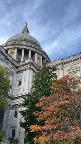 St Pauls Cathedral dome framed by vibrant orange autumn foliage under blue sky in London