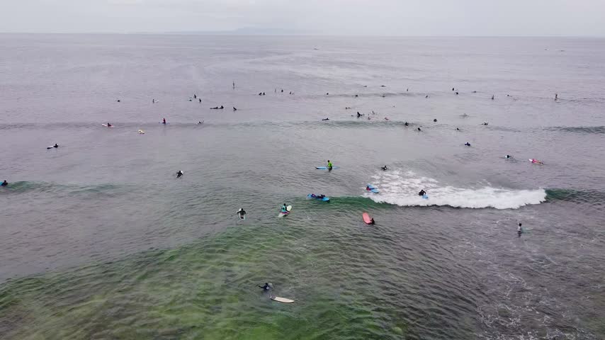 Aerial view of surfer catching and riding a wave in turquoise ocean water