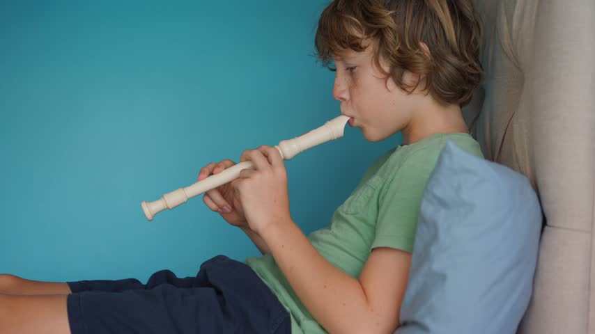 A little boy learns to play the flute at home, practicing with focus and enthusiasm in a cozy, warm setting. A charming scene of early musical exploration, creativity, and childhood growth.