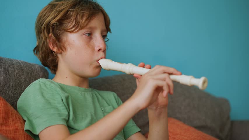 A little boy learns to play the flute at home, practicing with focus and enthusiasm in a cozy, warm setting. A charming scene of early musical exploration, creativity, and childhood growth.