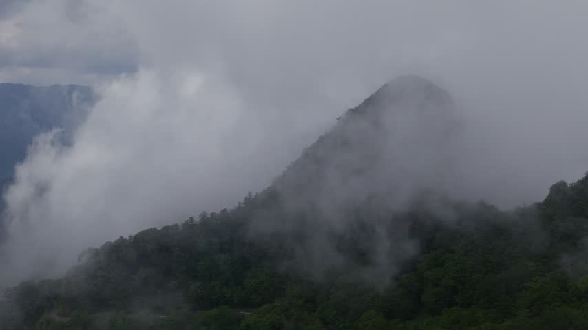 Aerial view of cloud and fog floating over green mountain peak on Shikoku, Japan