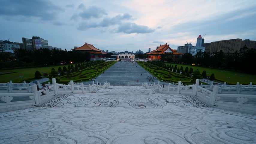 View of the National Chiang Kai-shek Memorial Hall plaza at dusk in Taipei, Taiwan, featuring traditional Chinese architecture and gardens.
