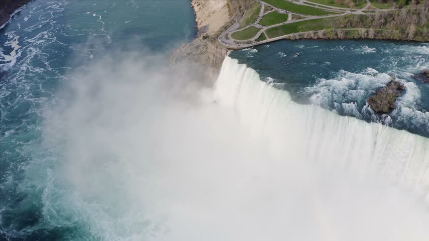 Aerial view of the powerful Niagara Falls with mist rising from the cascading water and surrounding parkland in Niagara Falls, Ontario, Canada.