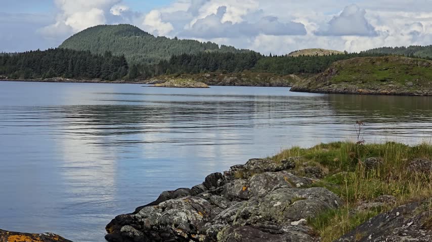  Large Coastal Rocks in Foreground with Dark Distant Shoreline and Forest.
Norway, Alver. September