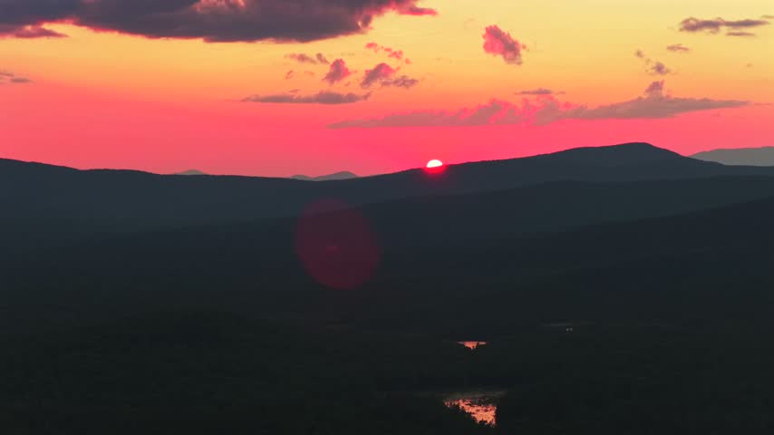 Adirondack Mountains river Schroon Lake vibrant sunset golden hour red fire sun on horizon clouds New York State aerial drone high peaks layers Mount Severance Pharaoh Lake Wilderness forwards up