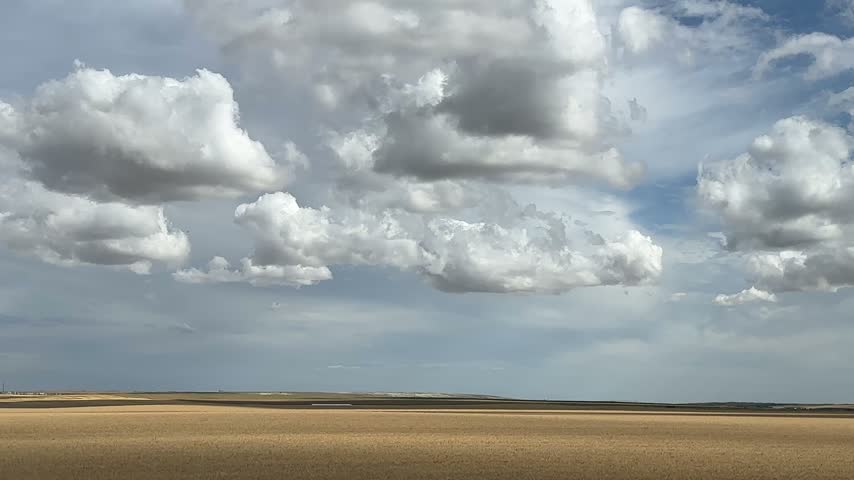 Scenic White Fluffy Clouds Over Expansive Farmland With Open Agricultural Fields, Rural Prairie Countryside and Blue Sky
