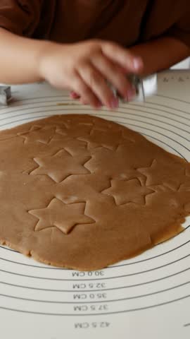 Close-up of child making star shaped gingerbread cookies for Christmas Holiday Baking.