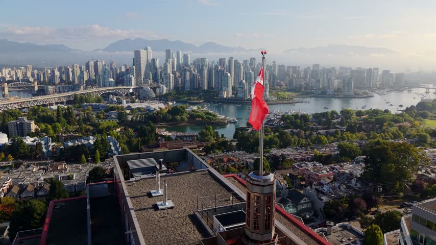 Downtown skyline of Vancouver captured with the Canadian flag waving in British Columbia, Canada - drone shot