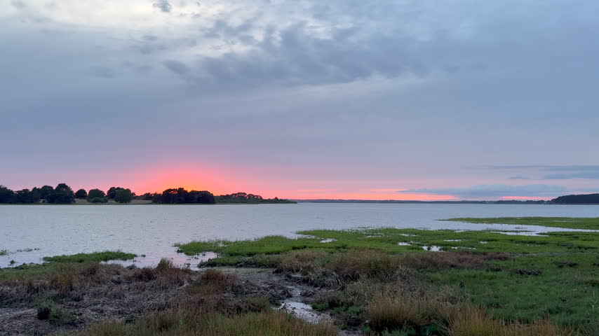 Cloudy sunset light over coastal salt marsh with wild grass and calm water in wetland reserve