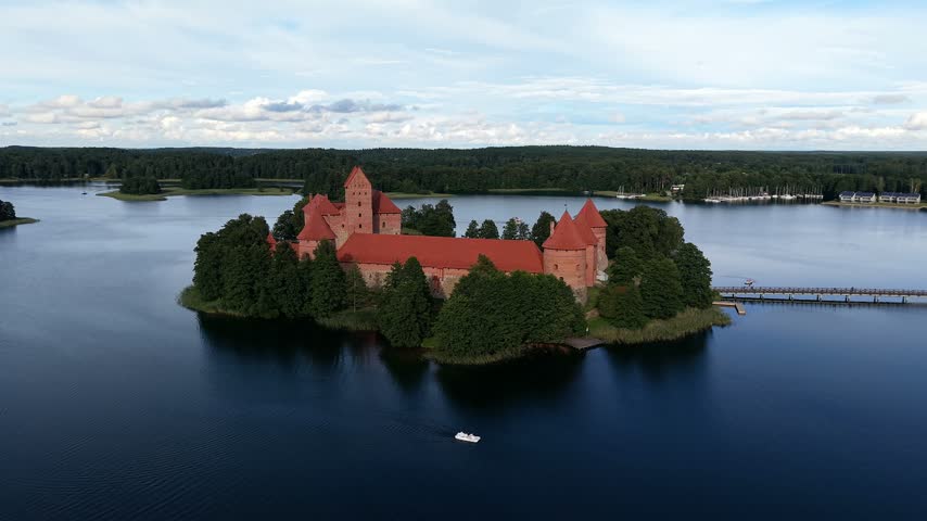 Aerial panoramic view of medieval Olavinlinna Castle surrounded by Lake Saimaa under a blue sky in Savonlinna, Finland.