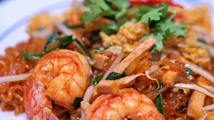 Close-up of freshly cooked Pad Thai with plump shrimp, rice noodles, egg, bean sprouts, and crushed peanuts, presented as a flavorful Thai street food dish.