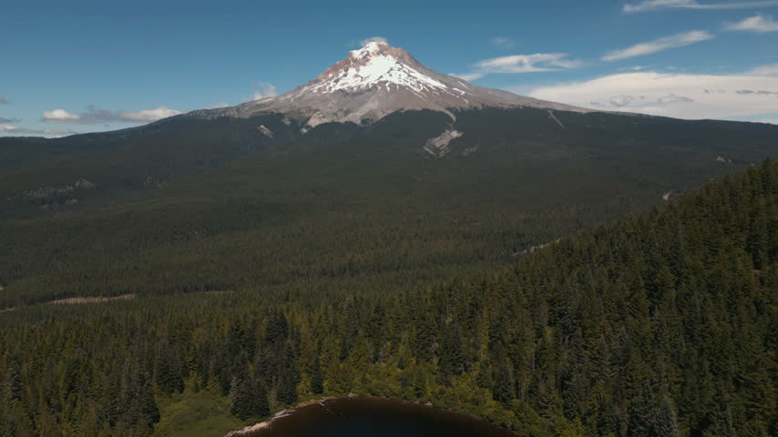 Snow-capped Mount Hood rises beyond vast evergreen wilderness near Mirror Lake, Oregon, drone panoramic dolly