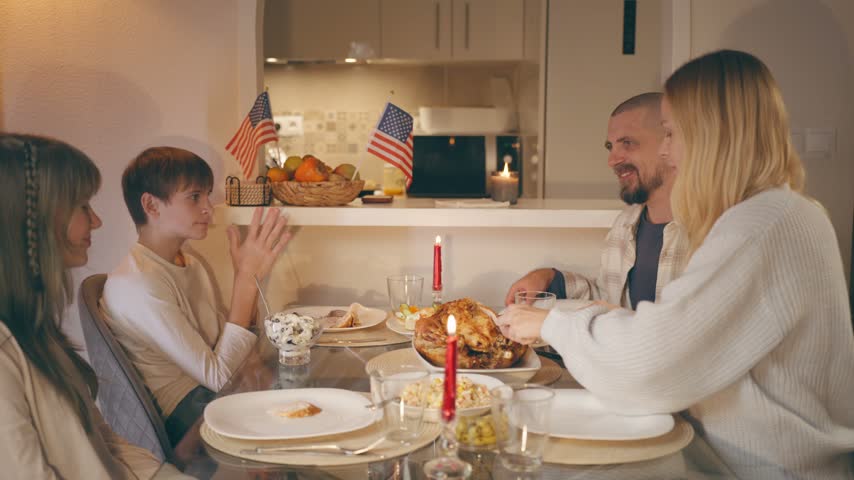 Cheerful american family gathers for a warm thanksgiving dinner at home, mother carving roasted turkey as parents and two children celebrate a cozy, festive holiday meal together