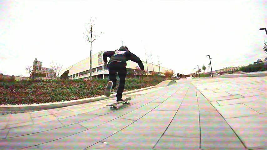 Young man skateboarding and doing a boardslide grind trick on a wooden ledge in a modern city park