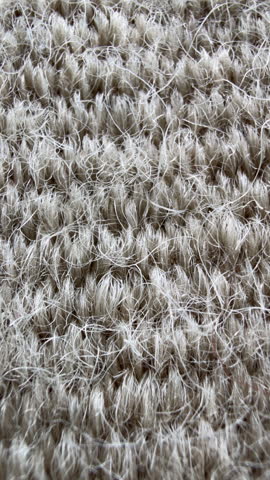 Close up of light beige wool texture in vertical format.