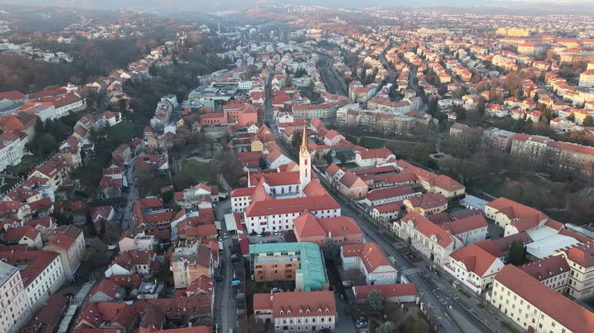 Aerial view of Zagreb Cathedral and the historic city center in Croatia. Cinematic drone shot of the gothic church towers, red rooftops, and urban skyline during daylight.