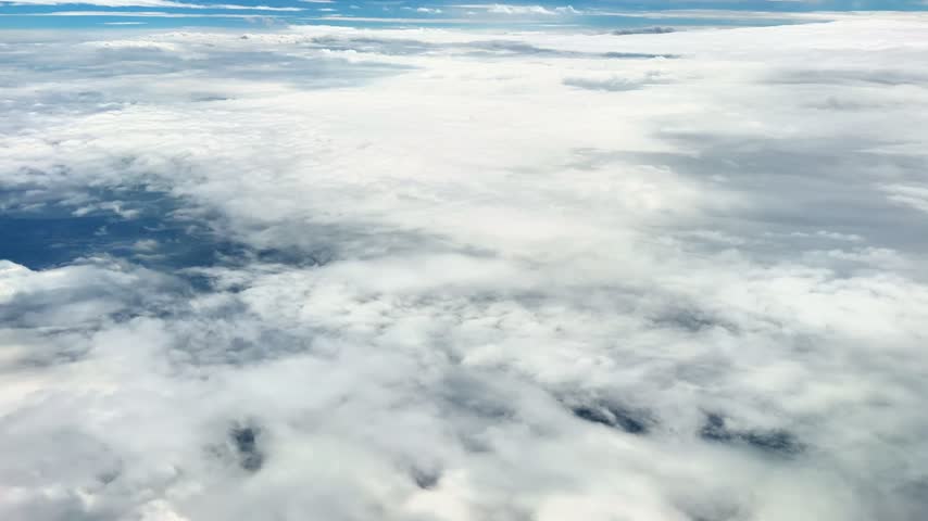 A plane is flying from Dhaka, Bangladesh to New York, cutting through the clouds. Idle moments are spent on the plane, waiting for the destination. A wonderful moment of seeing the world from the sky!