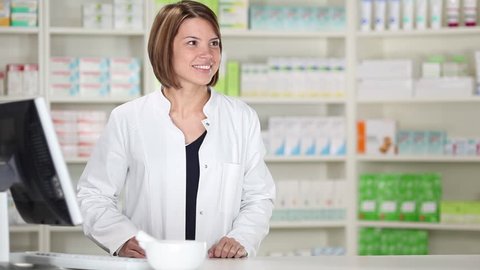 Young female pharmacist with customer at pharmacy