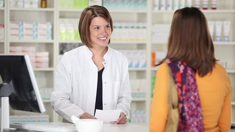 Friendly talk in the pharmacy between two females - saleswoman looks after drug