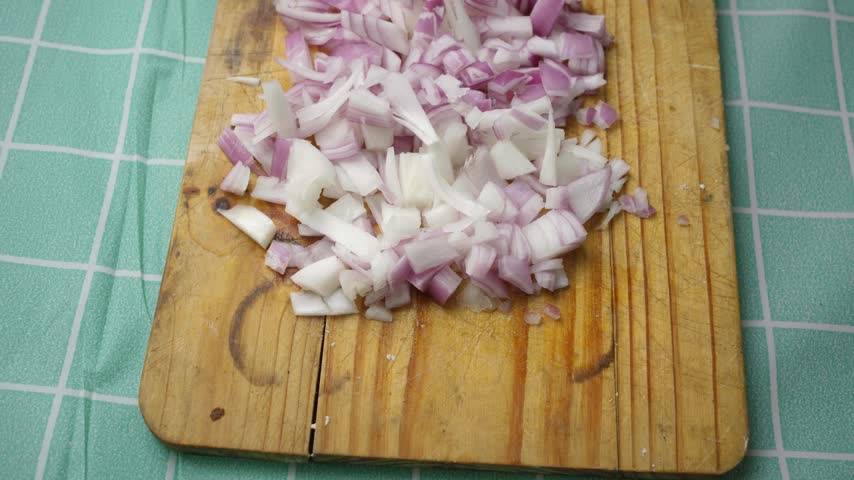 Close up view of finely chopped red onion on a rustic wooden table