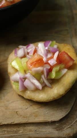 Panning view of a rustic platter with homemade sopaipillas and fresh pebre sauce, vertical view