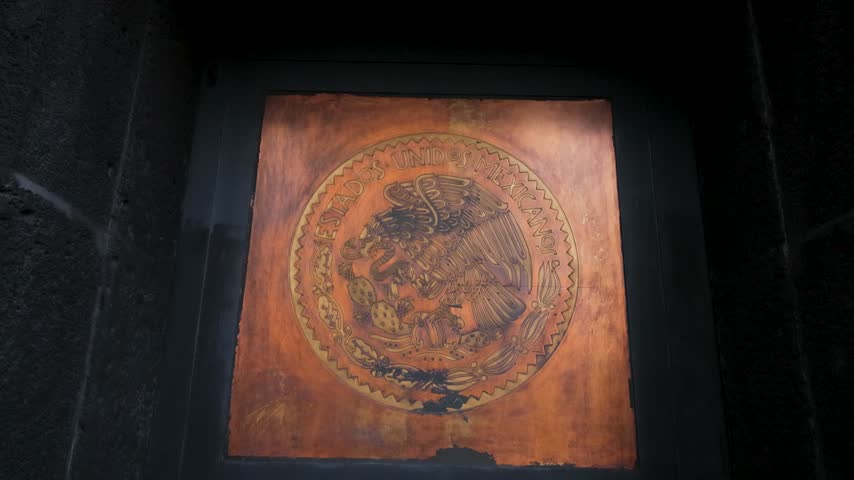 Detailed view of the Mexican national emblem engraved on a weathered metal panel at the Monument to the Revolution in Mexico City.