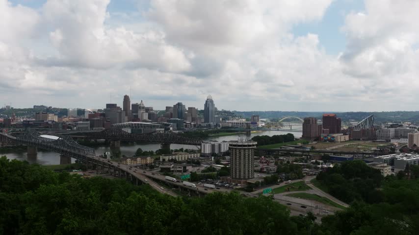 Downtown Cincinnati skyline, Ohio River and highway network under cloudy sky, aerial establishing backdrop dolly