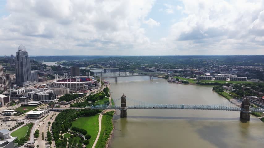 Ohio River and downtown Cincinnati waterfront with bridges and stadium, aerial pullback reveal