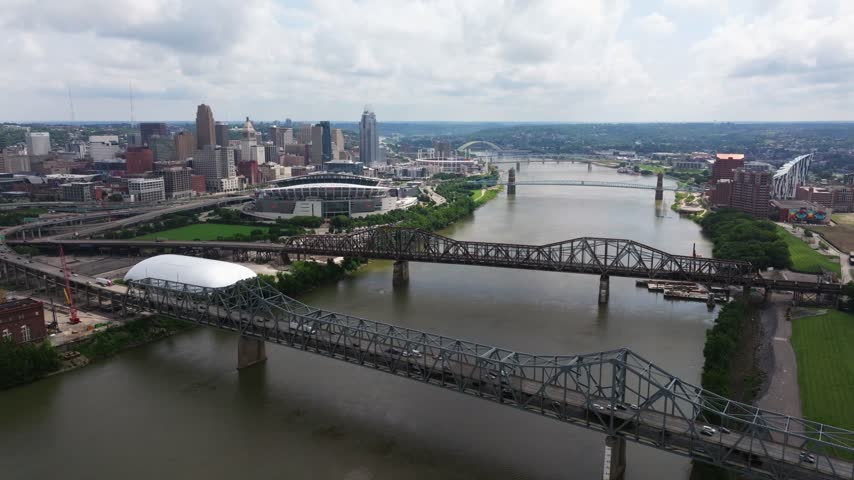 Multiple bridges crossing Ohio River beside downtown Cincinnati skyline, aerial dolly over water