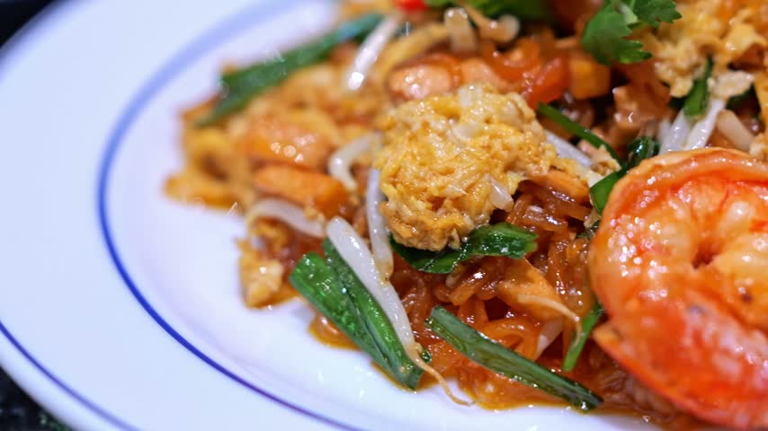 Close-up of freshly cooked Pad Thai with plump shrimp, rice noodles, egg, bean sprouts, and crushed peanuts, presented as a flavorful Thai street food dish.