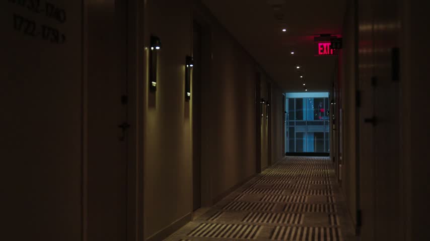 Dimly lit modern hotel hallway with patterned carpet and exit sign in Los Angeles California