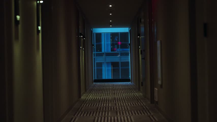 Dimly lit modern hotel hallway with patterned carpet and exit sign in Los Angeles California