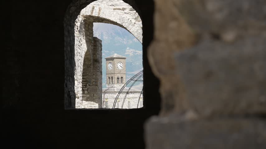 View of clock tower at Gjirokastër Castle in southern Albania framed through old stone archway
