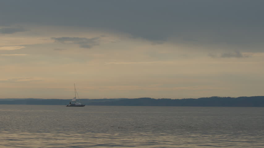 Sailing boat moves on the lake with during sunset