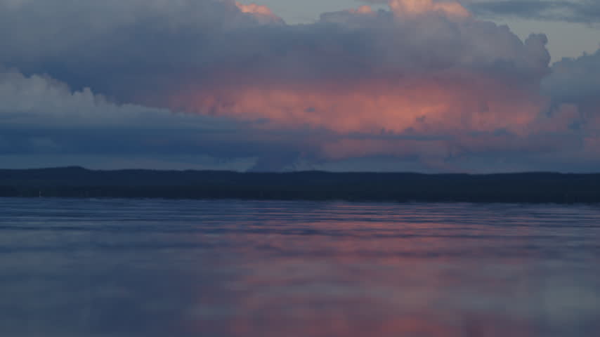 Surface of the river with calm waves and pink clouds in the sky