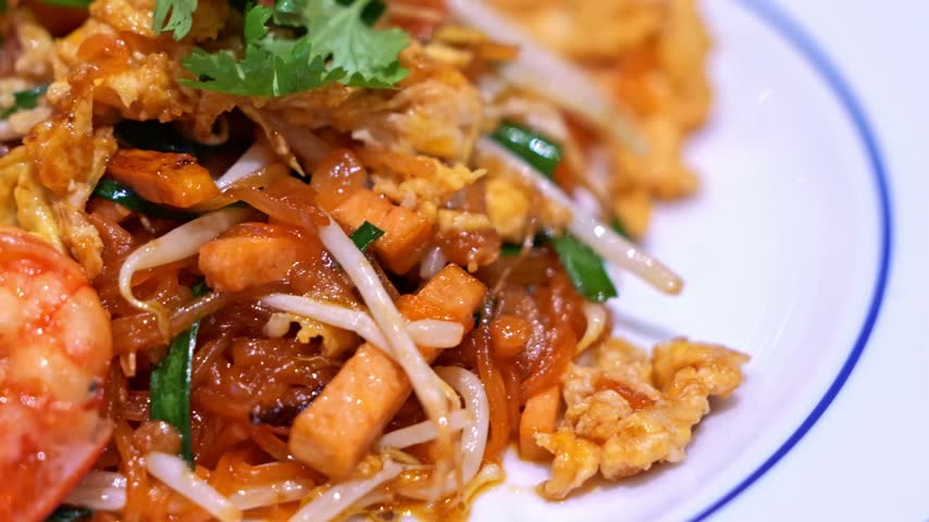 Close-up of freshly cooked Pad Thai with plump shrimp, rice noodles, egg, bean sprouts, and crushed peanuts, presented as a flavorful Thai street food dish.