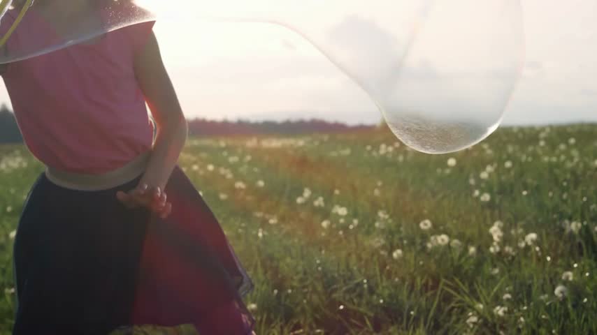 A large soap bubble floats through the air before gently disappearing, creating a playful, delicate scene with shimmering reflections and a dreamy atmosphere.