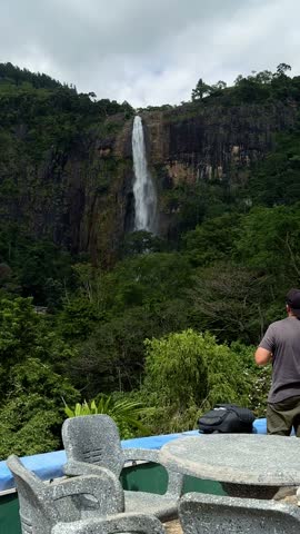Man taking photos of majestic Diyaluma waterfall with camera in Sri Lanka.