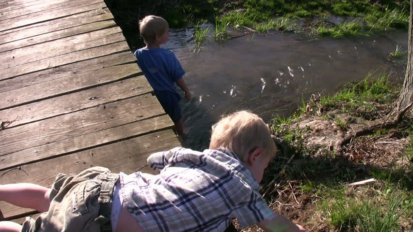 Boys play and wade in flowing creek