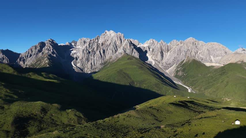 Landscape of green grassland and beautiful lake in high altitude mountain top, with snowcapped mountains in the distance	