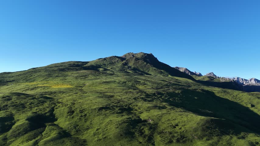 Landscape of green grassland and beautiful lake in high altitude mountain top, with snowcapped mountains in the distance	
