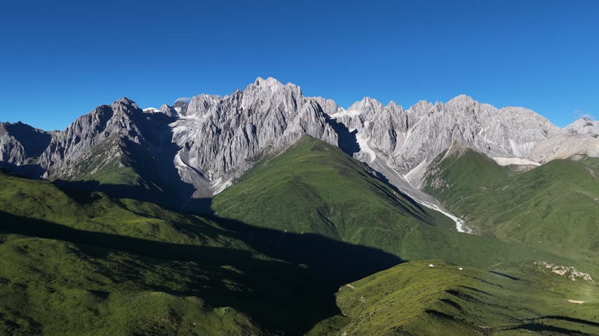 Landscape of green grassland and beautiful lake in high altitude mountain top, with snowcapped mountains in the distance	