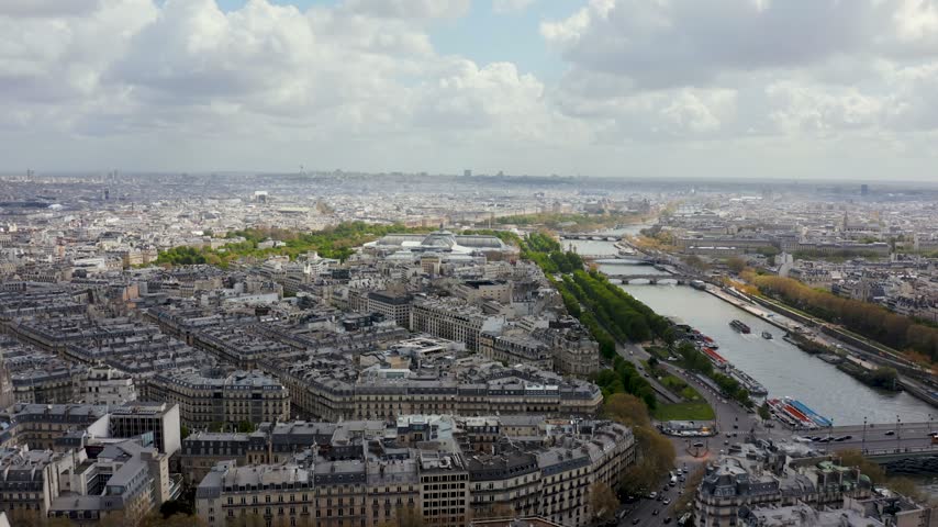 Aerial view of the Seine river winding through the historic cityscape of Paris, with dense urban architecture and bridges under a cloudy sky in Paris, Ile-de-France, France.