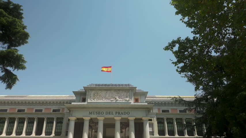 A wide shot of the iconic Museo del Prado facade under a clear blue sky in Madrid, Spain. Suitable for travel documentaries, art history content, and European tourism promotions.